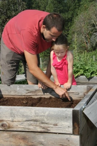 Planting seeds in the planter box with a little helper.